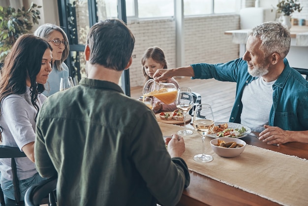 Família feliz de várias gerações se comunicando e sorrindo enquanto jantam juntos