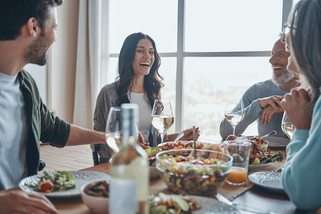 Família feliz de várias gerações se comunicando e sorrindo enquanto jantam juntos