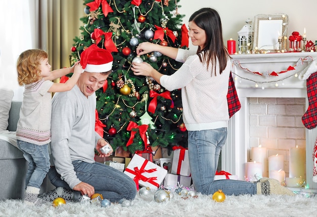 Família feliz decorando a árvore de Natal na sala de estar do feriado