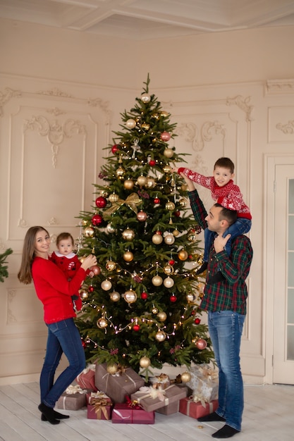 Familia feliz decorando el árbol de Navidad en el interior juntos