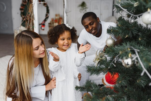 Familia feliz decorando el árbol de Navidad