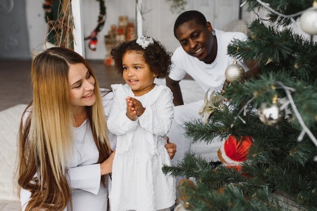 Familia feliz decorando el árbol de Navidad