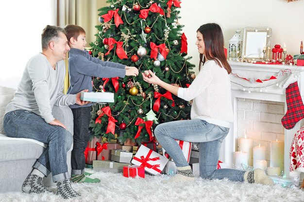 Familia feliz decorar el árbol de Navidad en la sala de vacaciones