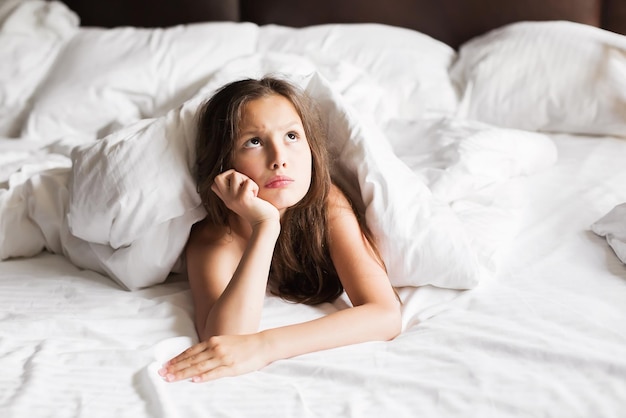 Família feliz deitada debaixo do cobertor na cama em casa