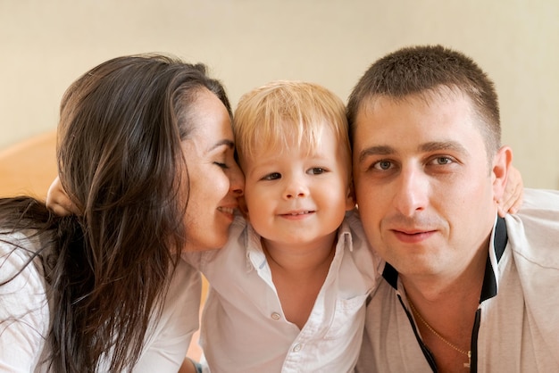 Foto família feliz deitada na cama e abraçando mãe, pai e filhozinho.