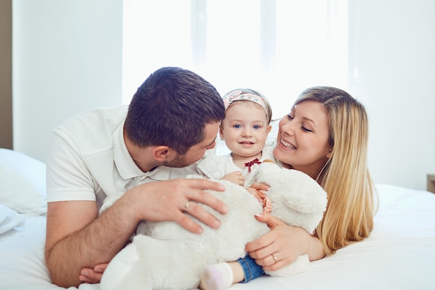 Foto família feliz deitada na cama no quarto.