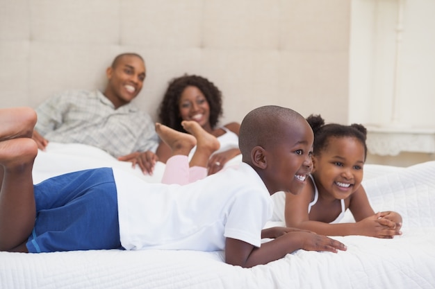 Família feliz deitada na cama, sorrindo