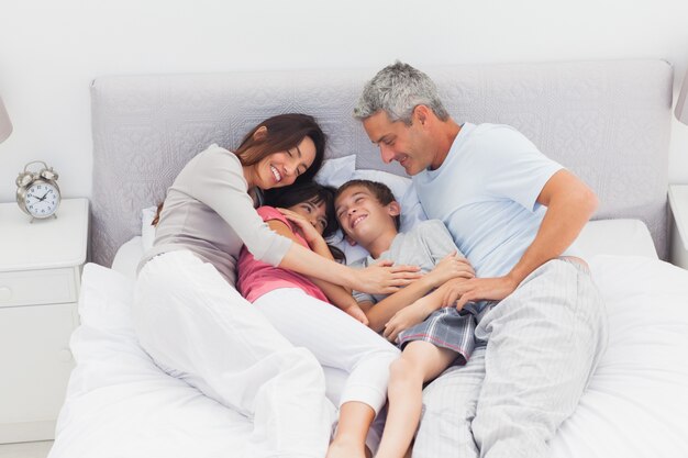 Família feliz deitada na cama