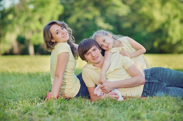 Família feliz deitada na grama do parque.