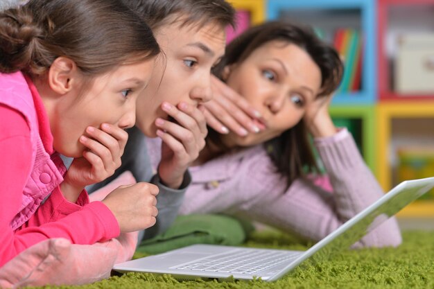 Família feliz deitada no chão em frente ao laptop