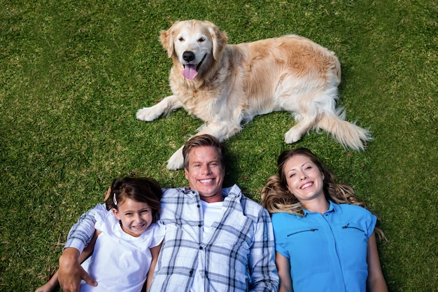 Foto família feliz, deitado grama de íons com seu cachorro