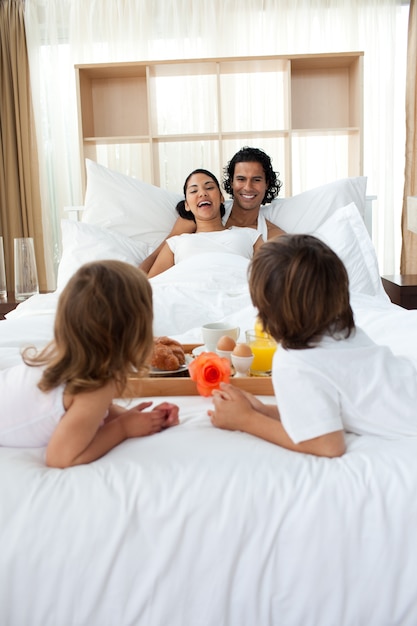 Foto familia feliz desayunando acostado en la cama