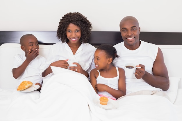 Familia feliz desayunando en la cama