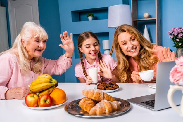 Familia feliz desayunando por la mañana en casa mientras tiene una videollamada