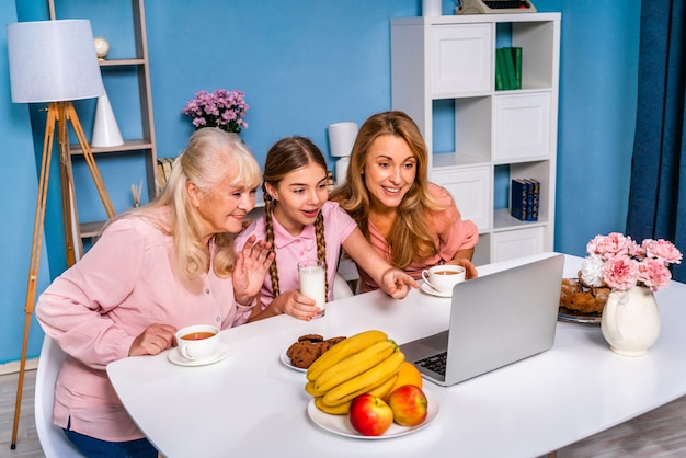 Familia feliz desayunando por la mañana en casa mientras tiene una videollamada