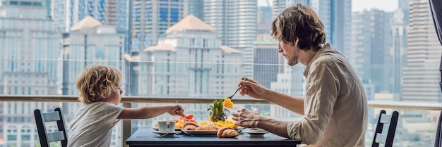 Familia feliz desayunando en la mesa de desayuno del balcón con fruta de café y croissant de pan en