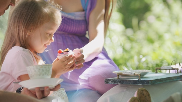 Familia feliz desayunar al aire libre en el parque verde - madre, padre e hija, teleobjetivo