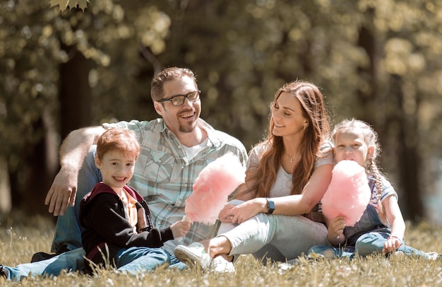 Familia feliz descansando en el césped de la ciudad Parkthe concepto de entretenimiento familiar