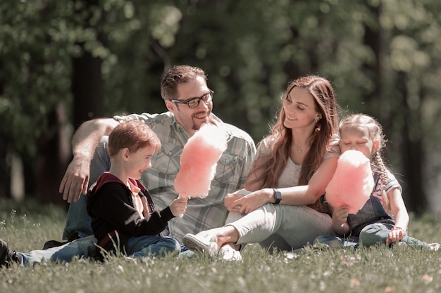 Familia feliz descansando en el césped del parque de la ciudad