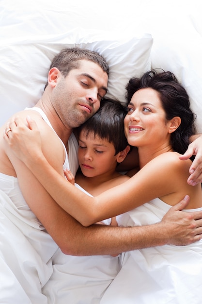 Família feliz descansando na cama