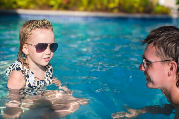 Familia feliz descansando en la piscina