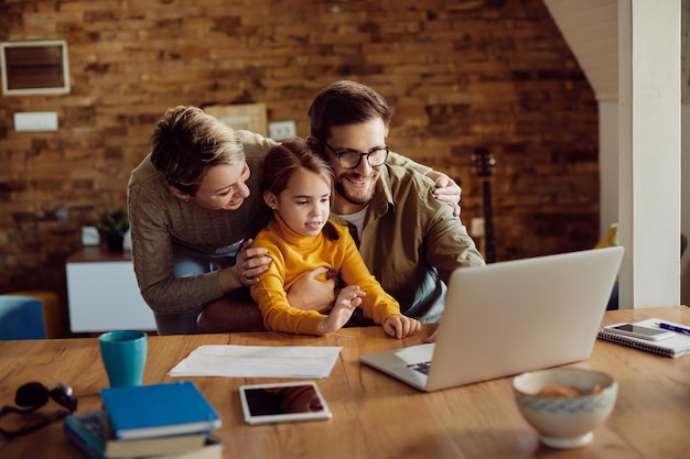 Família feliz desfrutando enquanto usa laptop em casa