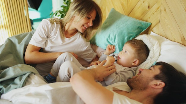 Familia feliz despierta y juega en la cama en casa