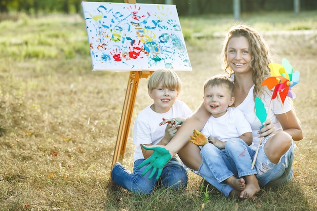 Familia feliz dibujo al aire libre. Joven madre divirtiéndose con sus hijos pequeños