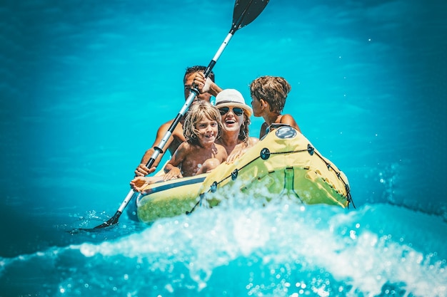 La familia feliz disfruta remando en kayak amarillo en el agua del océano tropical durante las vacaciones de verano. Están navegando en kayak en el mar.