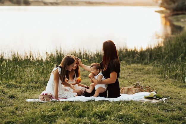 Familia feliz disfrutando de un picnic en la naturaleza cerca del río