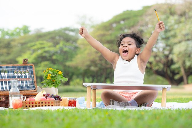 Una familia feliz disfrutando de un picnic en el parque Una niña se está divirtiendo dibujando en papel colocado en la mesa