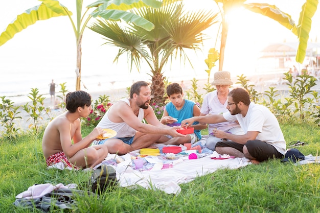 Familia feliz disfrutando de un picnic en la playa cerca del mar