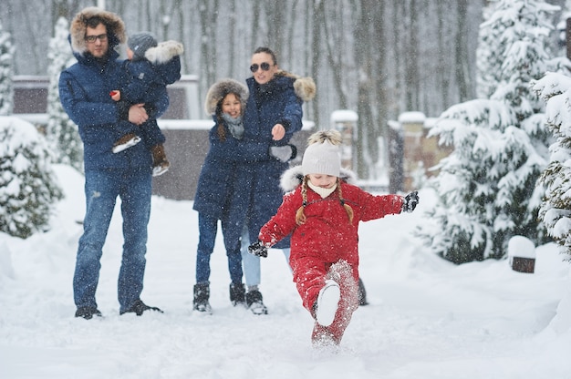 Familia feliz divertirse afuera cerca de la casa en invierno