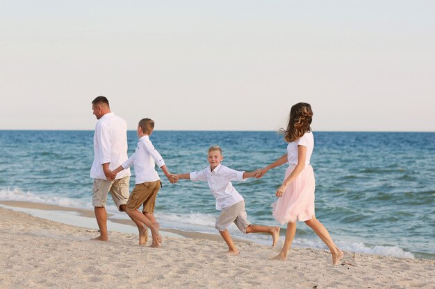 Familia feliz divertirse caminando en la playa.