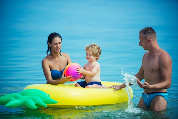 Familia feliz divertirse con colchón de aire en la playa.