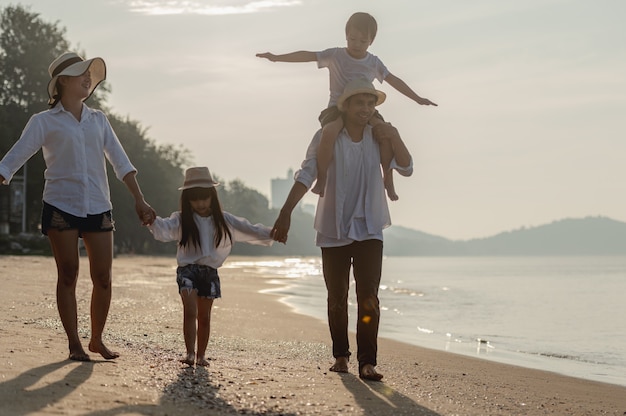 Familia feliz se divierten en la playa al atardecer Padre, madre e hijos jugando juntos