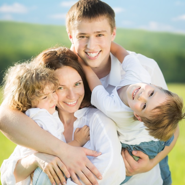 Familia feliz divirtiéndose al aire libre en el campo de primavera contra el fondo de cielo azul