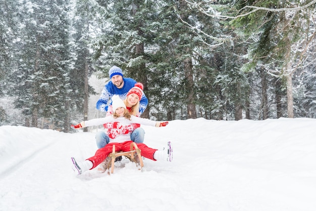 Familia feliz divirtiéndose al aire libre, la madre y el padre del niño jugando en invierno estilo de vida saludable