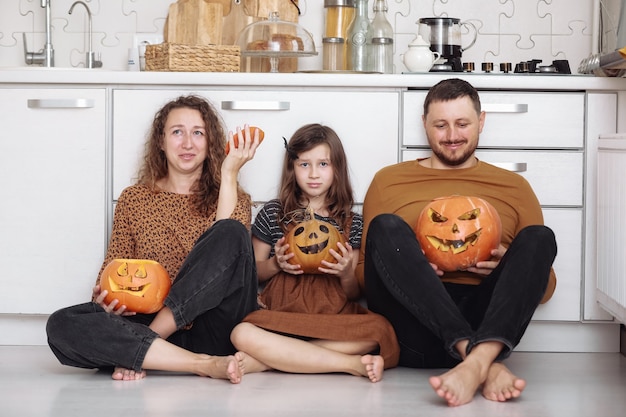 Familia feliz divirtiéndose en casa con calabazas para Halloween