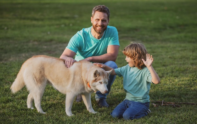 Familia feliz divirtiéndose con perro husky padre feliz y su hijo jugando con perro en el parque