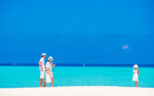 Familia feliz divirtiéndose en la playa blanca