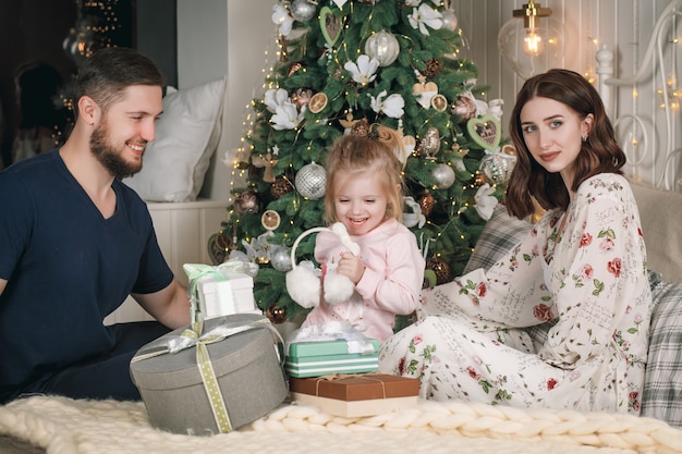 Familia feliz divirtiéndose con regalos de Navidad en casa