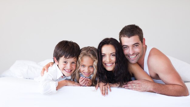 Familia feliz divirtiéndose tumbado en la cama