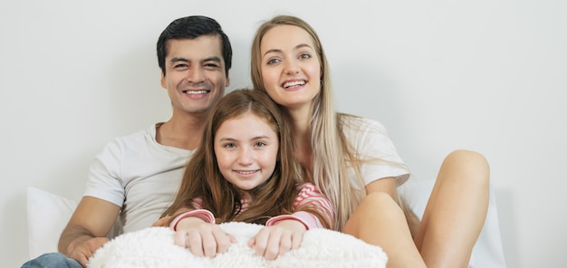 Família feliz do retrato que passa o tempo junto na cama no quarto.