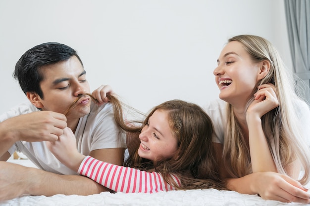 Foto família feliz do retrato que passa o tempo junto na cama no quarto.