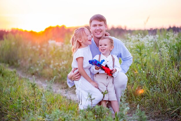 Familia feliz con dos hijos en el campo al atardecer, horario de verano.