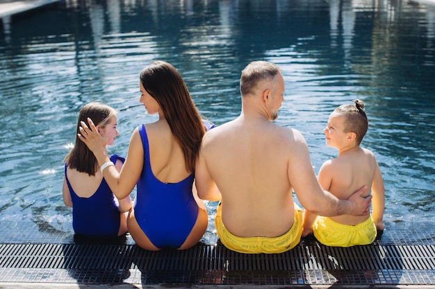 Familia feliz con dos niños divirtiéndose en la piscina Concepto de vacaciones de verano