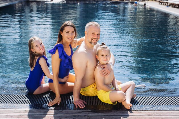 Familia feliz con dos niños divirtiéndose en la piscina Concepto de vacaciones de verano