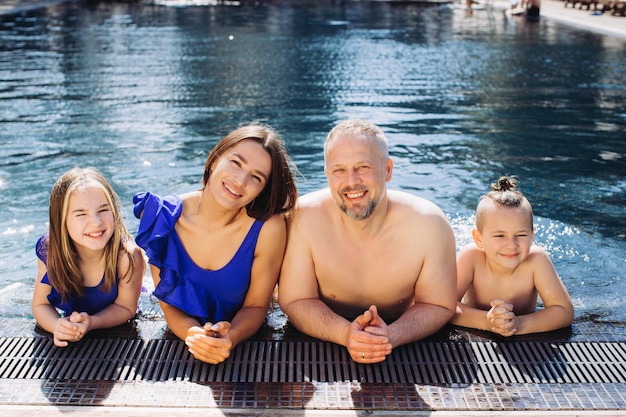 Familia feliz con dos niños divirtiéndose en la piscina Concepto de vacaciones de verano