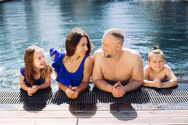 Familia feliz con dos niños divirtiéndose en la piscina Concepto de vacaciones de verano